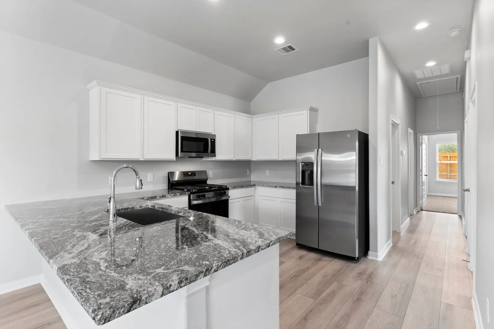 Kitchen with white cabinets and granite counters at Lake Conroe Village, Montgomery, TX