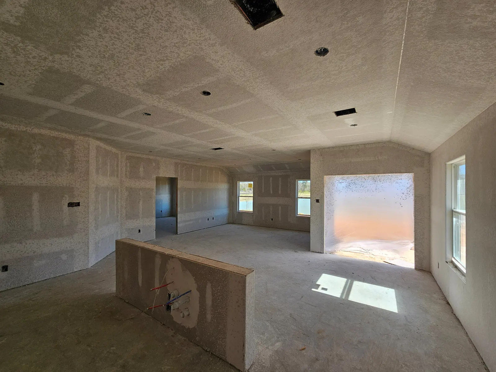Open living and kitchen area at drywall stage at 10715 Crockett Meadows, Conroe, TX