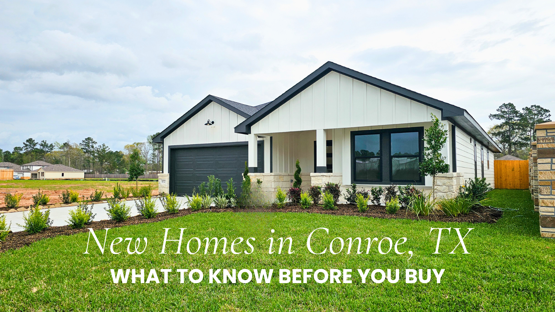 White modern farmhouse-style new home in Conroe TX with stone accents, dark windows, and lush green landscaping under a cloudy sky