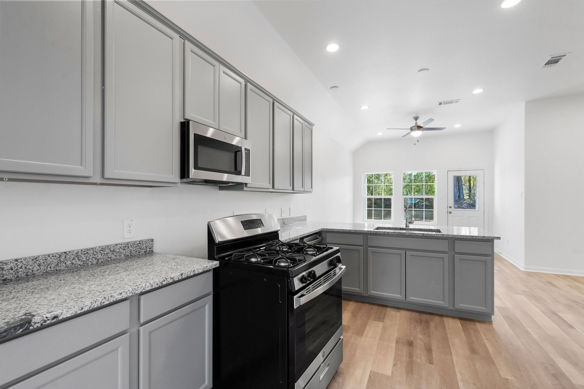Kitchen with gas range and grey cabinets at Cedar Crossing by Alta Homes